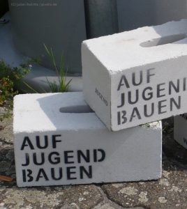 Weiße Gasbetonsteine mit schwarzer Aufschrift: "AUF JUGEND BAUEN"